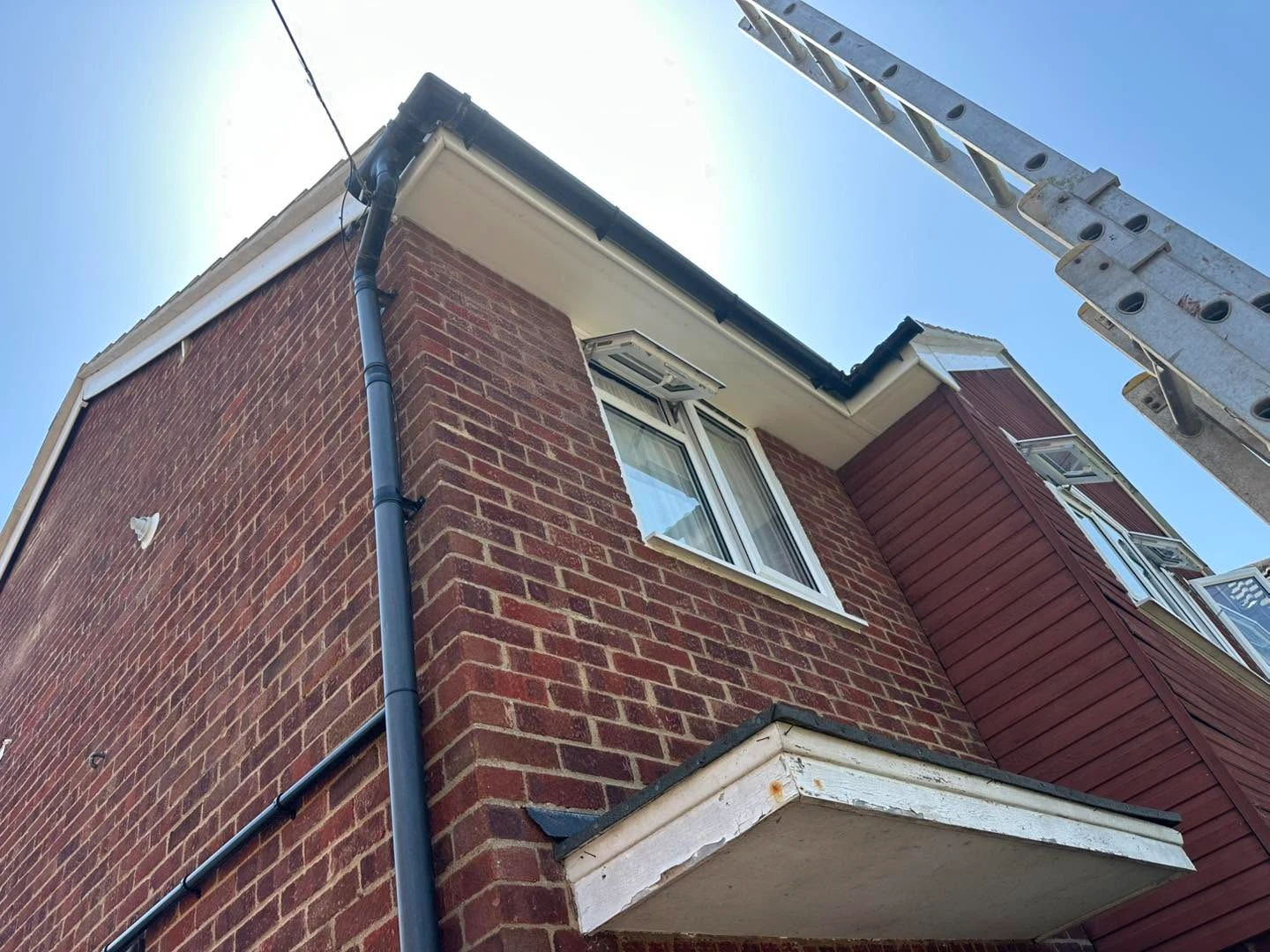 House with ladder cleaning the guttering.