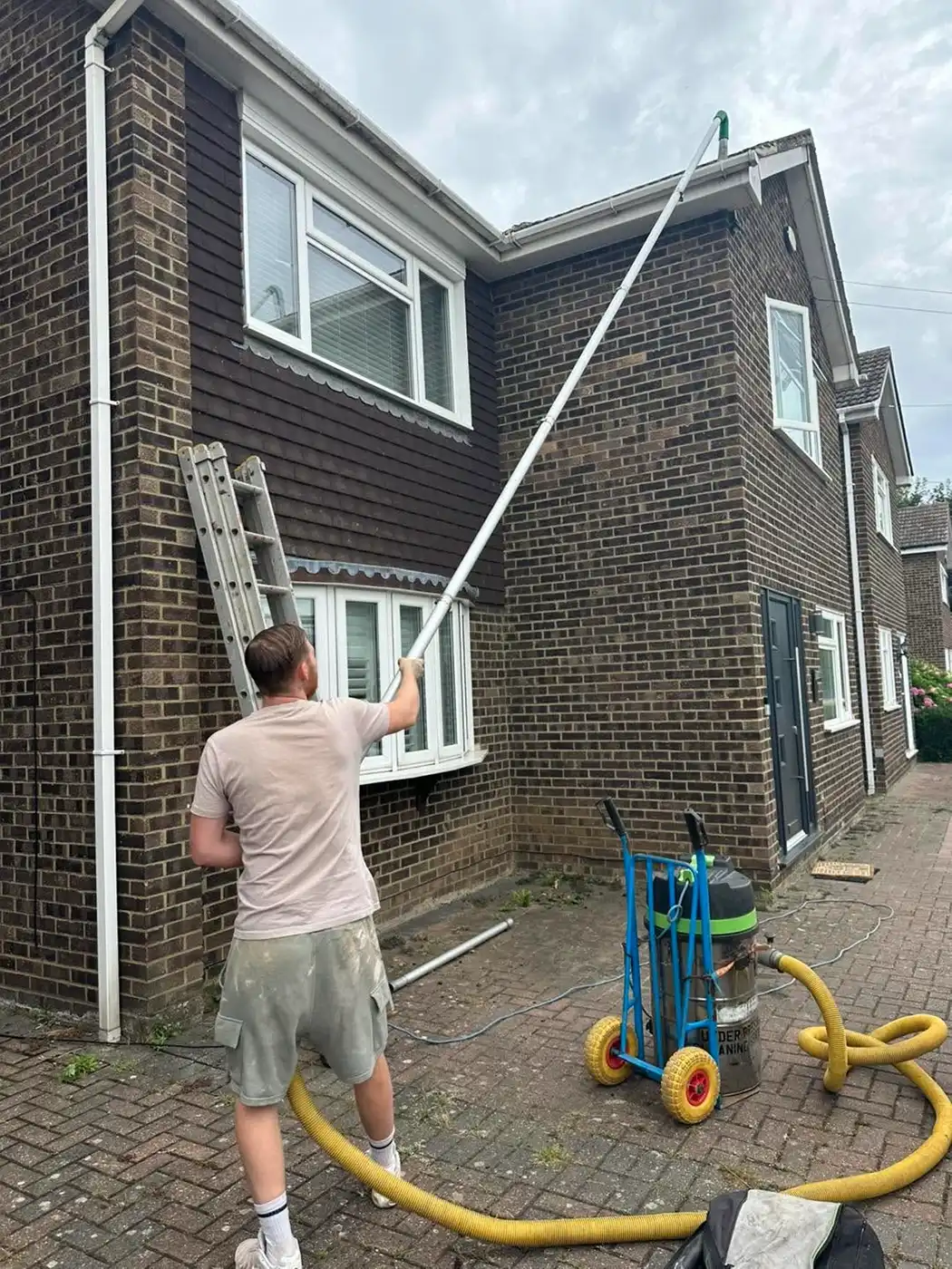 Man pressure washing the roof of a house.