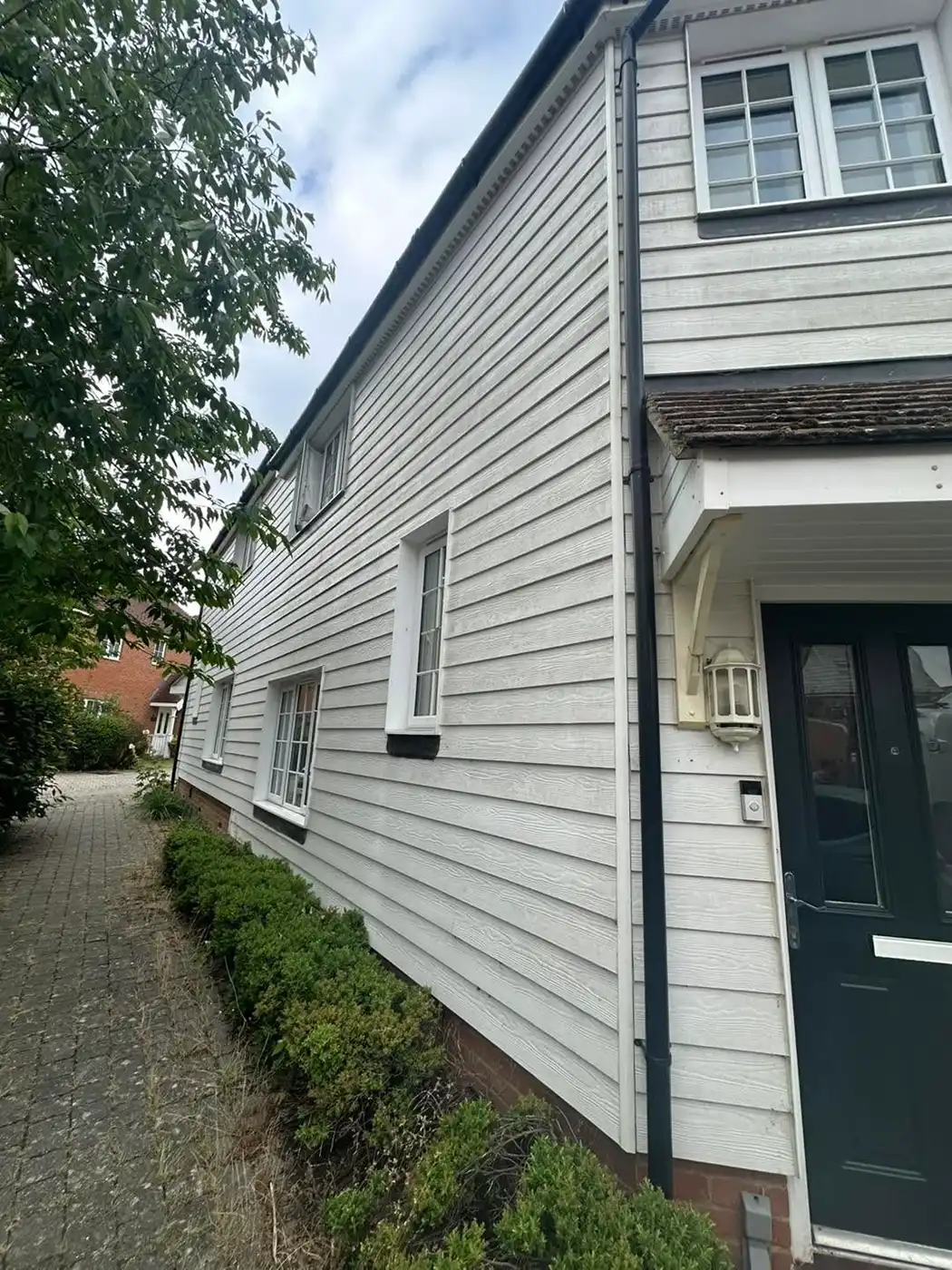 White slatted house with bushes outside.