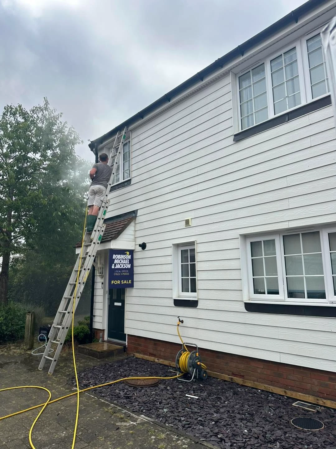 White house with ladder being cleaned.