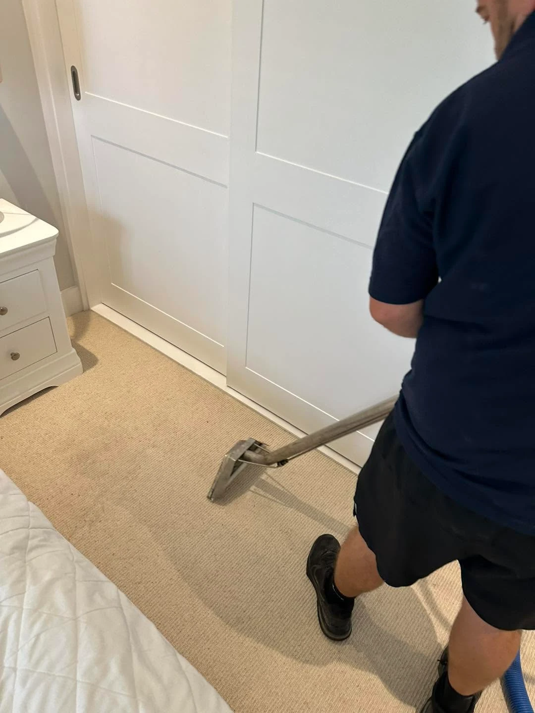 Man cleaning a beige carpet.